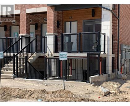 A black metal railing with a sign that says "RESERVED PARKING" is in front of a building.