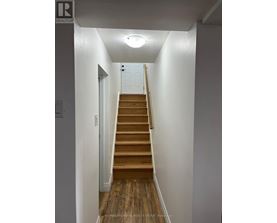 A hallway with a staircase leading to a door at the top.
