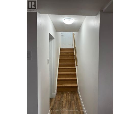 A hallway with a staircase leading to a door at the top.