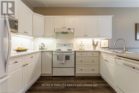 A clean, white kitchen with a refrigerator, oven, and sink.