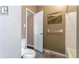 A bathroom with a toilet, a door, and a painting on the wall.