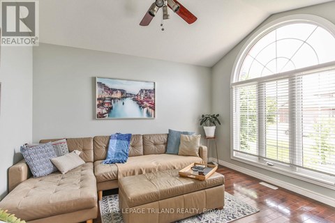 A living room with a large window and a painting of a cityscape on the wall.