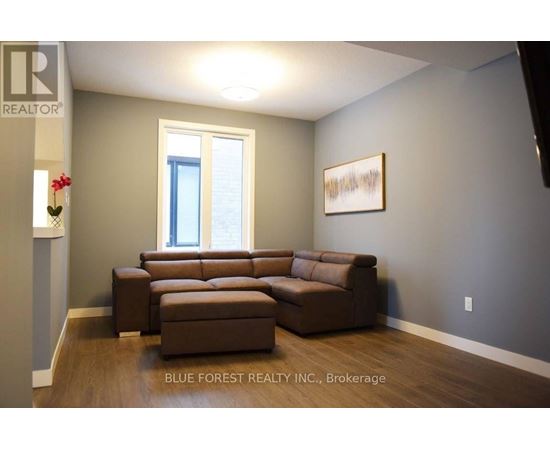 A living room with a brown couch and a painting on the wall.