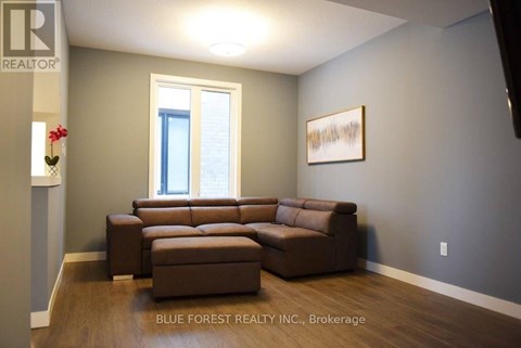 A living room with a brown couch and a painting on the wall.