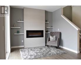 A grey chair is placed in front of a fireplace in a room.