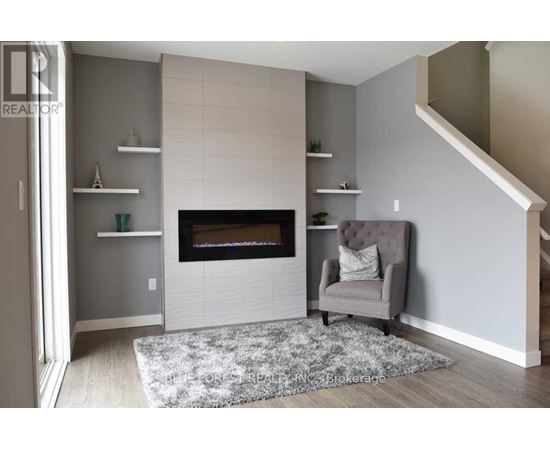 A grey chair is placed in front of a fireplace in a room.