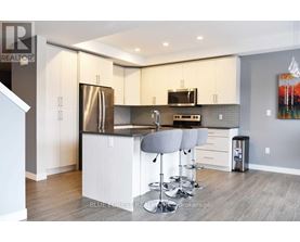 A modern kitchen with white cabinets and a wooden floor.