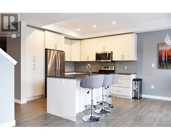 A modern kitchen with white cabinets and a wooden floor.