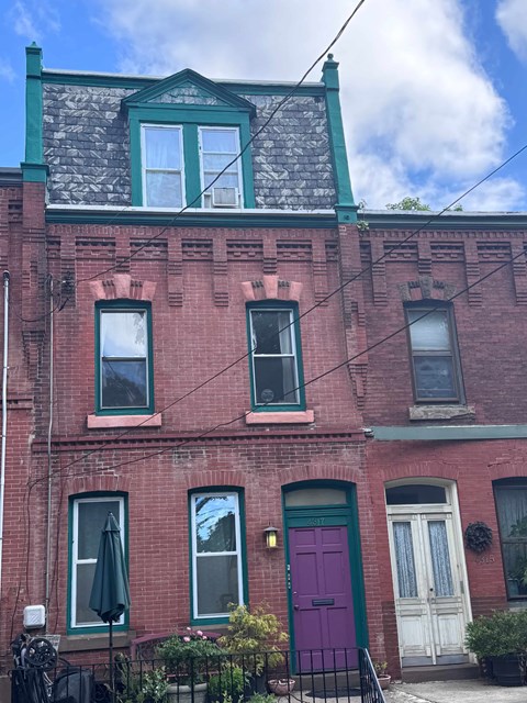 A red brick building with a green door and windows.