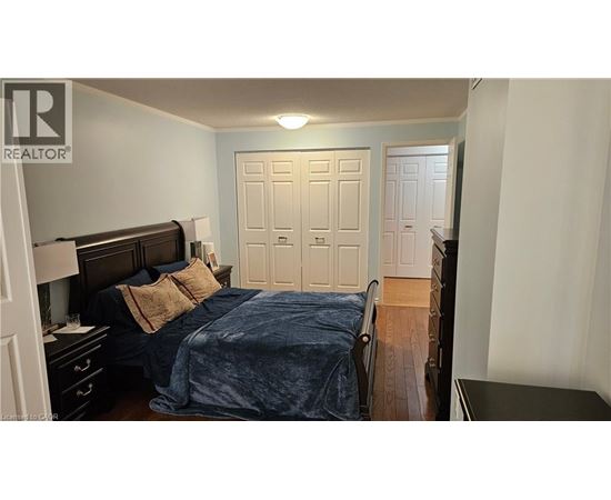 A bedroom with a bed, nightstand, and two doors.