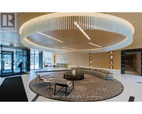 A modern living room with a circular light fixture and a patterned rug.