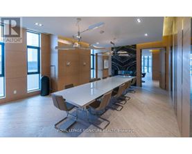 A conference room with a long table and chairs is shown.