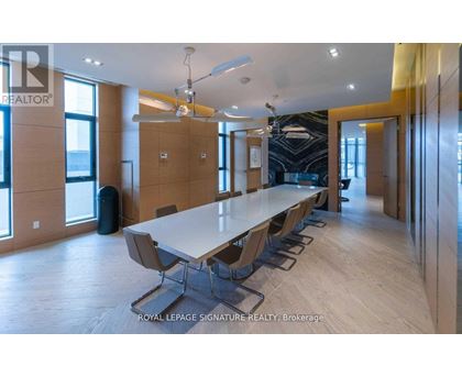 A conference room with a long table and chairs is shown.