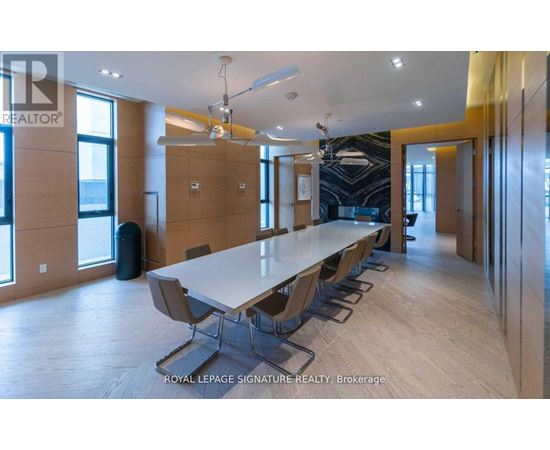 A conference room with a long table and chairs is shown.