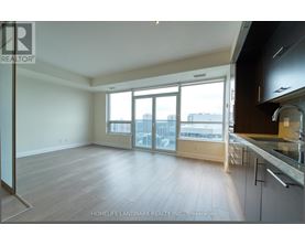 A spacious living room with a kitchen area to the right.