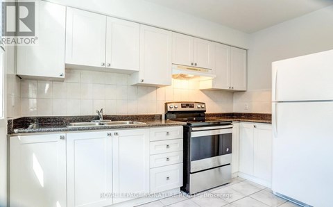 A kitchen with white cabinets and a black stove top oven.