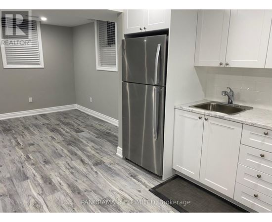 A kitchen with a stainless steel refrigerator and white cabinets.