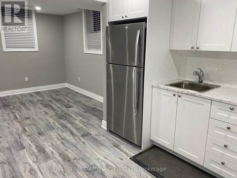 A kitchen with a stainless steel refrigerator and white cabinets.
