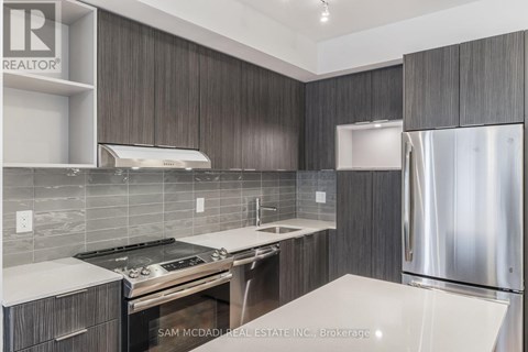 A modern kitchen with dark wood cabinets and stainless steel appliances.