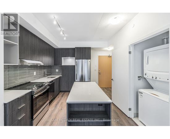 A modern kitchen with dark wood cabinets and stainless steel appliances.