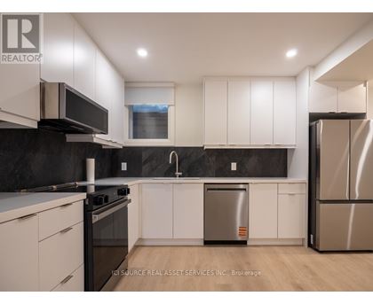 A modern kitchen with white cabinets and stainless steel appliances.
