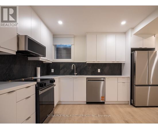 A modern kitchen with white cabinets and stainless steel appliances.