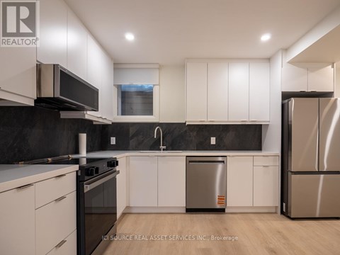 A modern kitchen with white cabinets and stainless steel appliances.