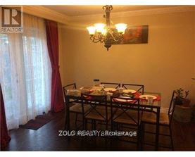A dining room with a table set for two and a chandelier hanging from the ceiling.