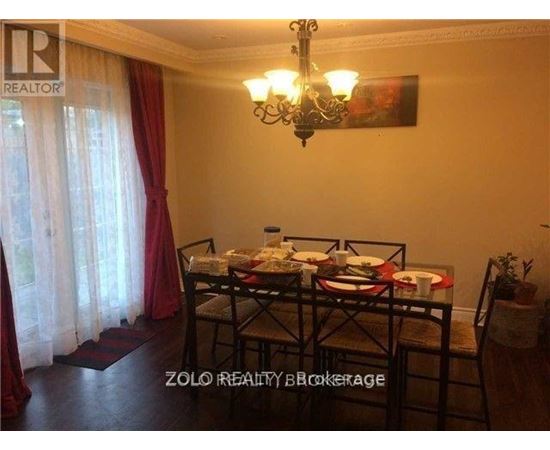 A dining room with a table set for two and a chandelier hanging from the ceiling.
