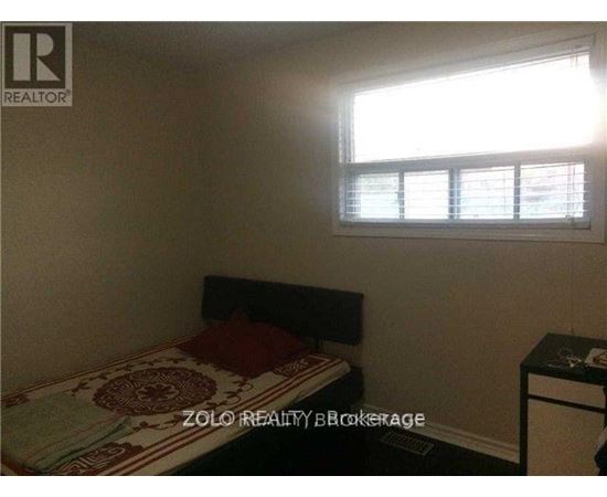 A bedroom with a bed, nightstand, and window with blinds.