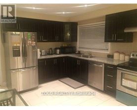 A kitchen with a stainless steel refrigerator and black cabinets.