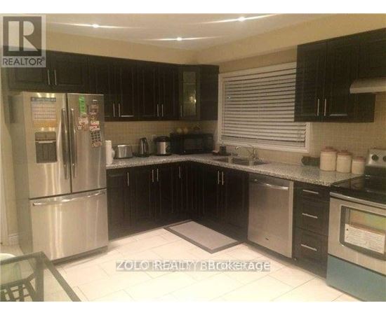 A kitchen with a stainless steel refrigerator and black cabinets.