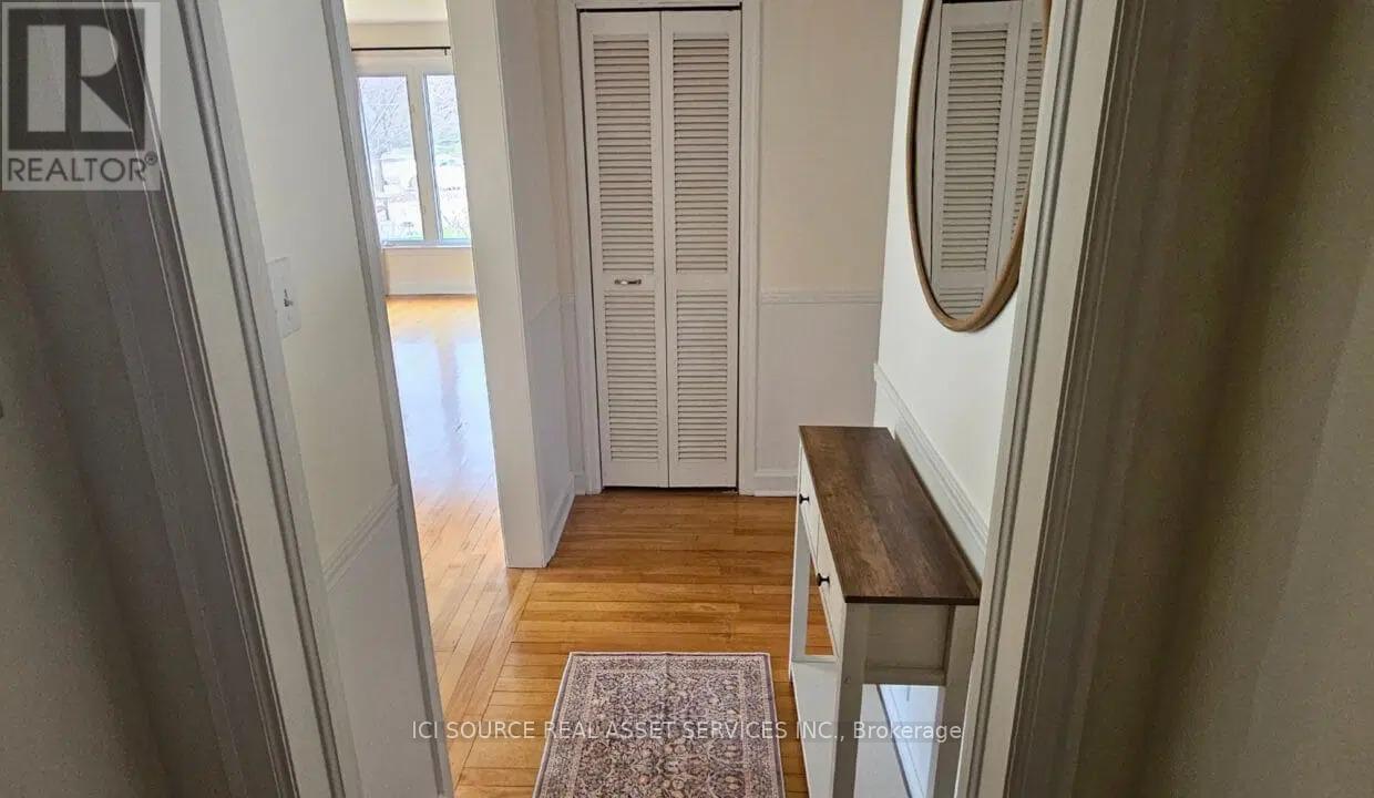 A hallway with a wooden floor and a rug in the middle.