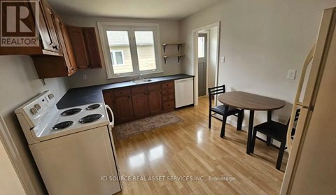 A kitchen with a stove, table and chairs.