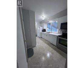 A kitchen with white appliances and a large window.