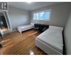 A bedroom with a white bed and wooden floors.
