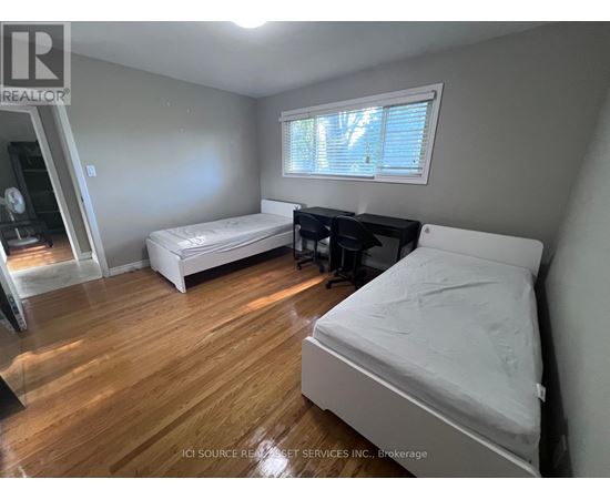 A bedroom with a white bed and wooden floors.