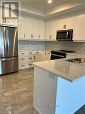 A kitchen with a white counter top and a stainless steel refrigerator.