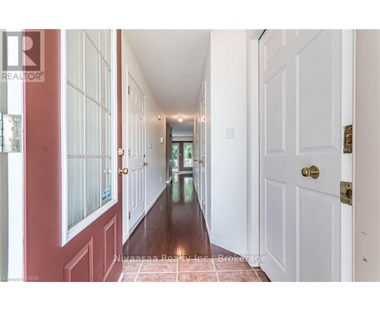 A hallway with white doors and a red door on the left.