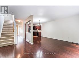 A spacious room with wooden floors and a staircase leading to another level.
