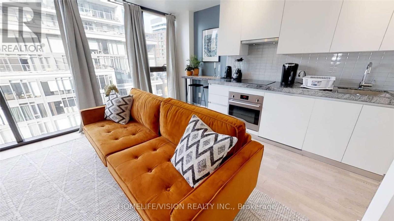 A living room with a brown couch and a window overlooking a city.
