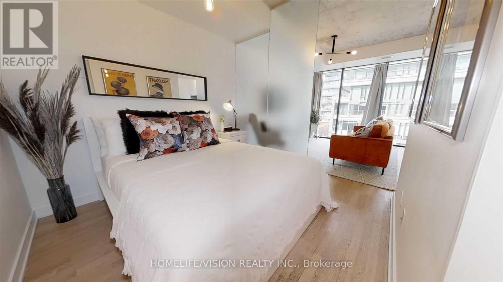 A bedroom with a white bed and a framed picture on the wall.