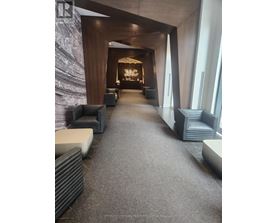 A hallway with a carpeted floor and a stone wall on the left side.