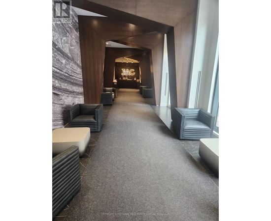 A hallway with a carpeted floor and a stone wall on the left side.