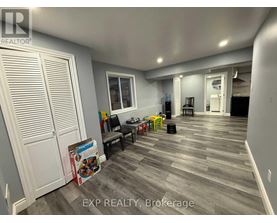 A room with a grey floor and white walls has a sign that says EXP REALTY, Brokerage.