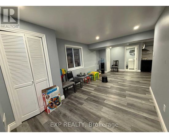 A room with a grey floor and white walls has a sign that says EXP REALTY, Brokerage.