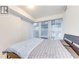 A bedroom with a bed and a window with blinds.