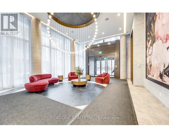A spacious lobby with red chairs and a large painting on the wall.