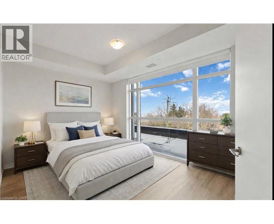 A bedroom with a large bed, a nightstand with a lamp, and a painting on the wall.