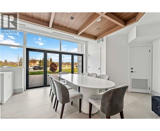 A dining room with a table and chairs and a view of the outside.